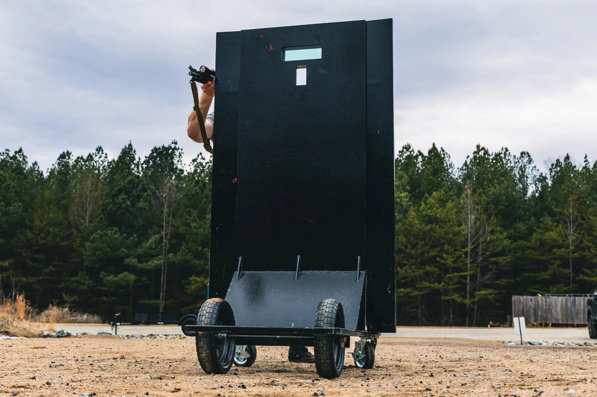 Level 4 ballistic shield with viewport and rolling base during field deployment